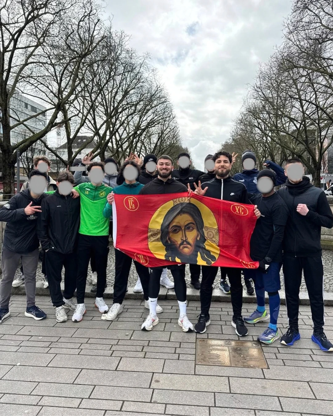 Luka mit Brüdern und einer Christus-Fahne beim Community Treffen in Düsseldorf