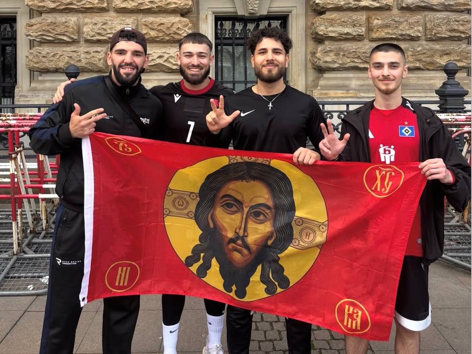 Vier RISE-UP-Brüder halten eine Christus-Fahne vor dem Hamburger Rathaus